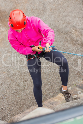 Fit girl abseiling down rock face