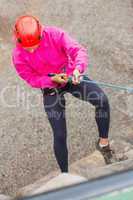 Fit girl abseiling down rock face