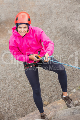 Happy girl abseiling down rock face