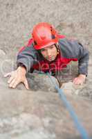 Focused man climbing rock face
