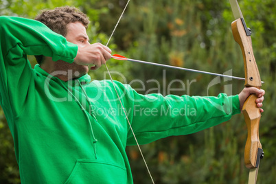 Man in green jumper about to shoot arrow