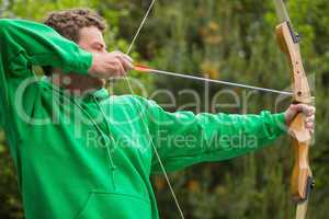 Man in green jumper about to shoot arrow