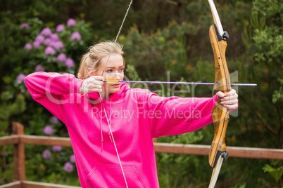 Concentrating blonde practicing archery