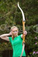 Concentrating blonde woman practicing archery