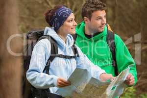 Smiling couple standing in a forest holding map