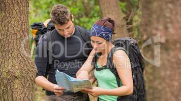 Fit couple reading map in a forest