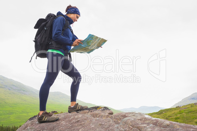 Woman standing on a rock reading map