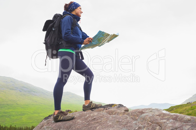 Woman standing on a rock holding map