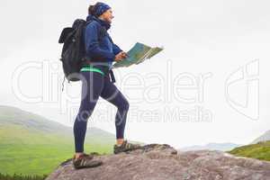 Woman standing on a rock holding map