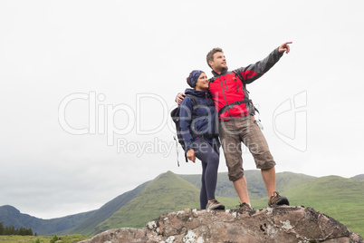 Couple standing on a rock looking at the mountains