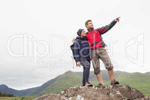 Couple standing on a rock looking at the mountains