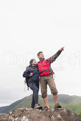 Couple standing on a rock looking up at the mountains