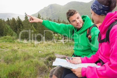 Couple sitting on a rock during hike using compass and map