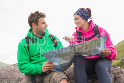 Couple using map and compass sitting on a rock