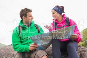 Couple using map and compass sitting on a rock