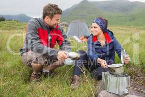 Couple cooking outside on camping trip and smiling
