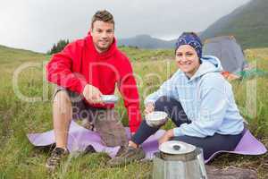 Couple cooking outside on camping trip smiling at camera