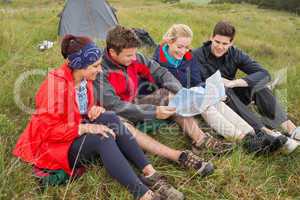 Friends sitting down looking at map on camping trip