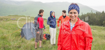 Brunette smiling at camera with friends behind her on camping tr