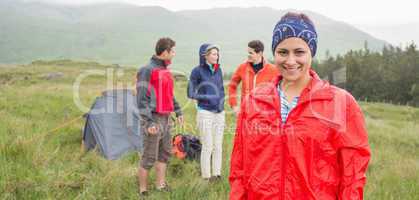 Brunette smiling at camera with friends behind her on camping tr