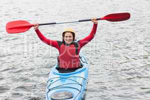 Smiling woman in a kayak cheering at the camera