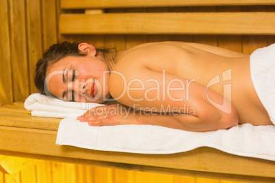 Happy brunette lying down in a sauna