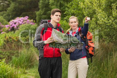Sporty couple on a hike holding map and pointing