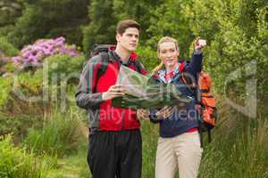 Sporty couple on a hike holding map and pointing