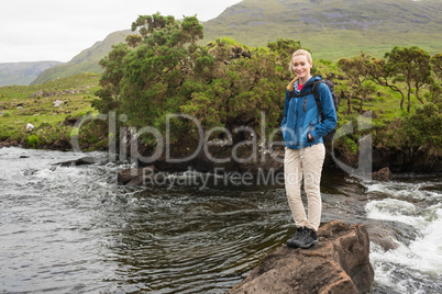 Blonde woman standing on a rock in a stream