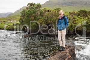 Blonde woman standing on a rock in a stream