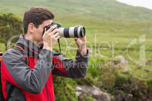 Handsome man on a hike taking a photograph