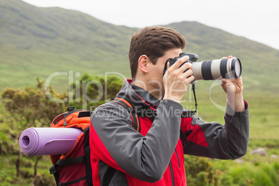 Sporty man on a hike taking a photograph