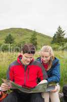 Cheerful couple taking a break on a hike to look at map