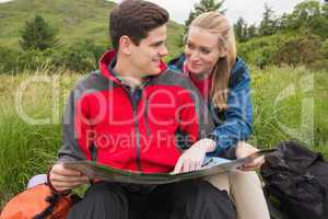 Smiling couple taking a break on a hike to look at map