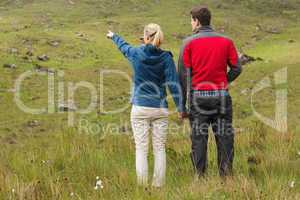 Couple holding hands with woman pointing on a walk