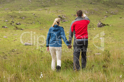 Couple holding hands on walk with man pointing