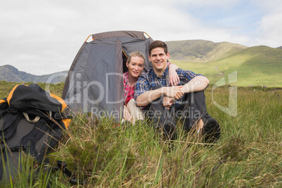 Couple sitting in their tent after a hike and smiling at camera