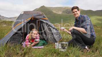 Smiling couple cooking outdoors on camping trip