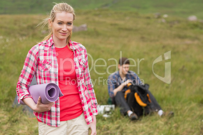 Happy woman carrying camping mat
