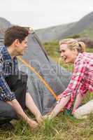 Smiling couple pitching their tent together