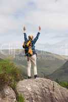 Woman standing on rock cheering after a hike