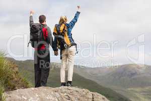 Excited couple reaching the top of their hike and cheering