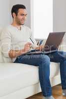 Smiling handsome man using his credit card to buy online