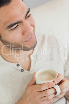 Smiling thoughtful man holding cup of coffee
