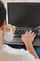 Over shoulder view of young man using his laptop