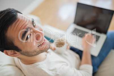 High angle view of smiling young man using his laptop