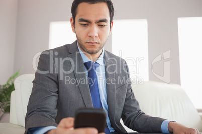Serious businessman sending a text message