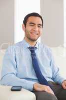 Cheerful young businessman sitting on cosy sofa