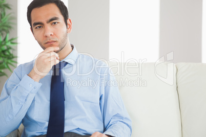 Thoughtful classy businessman sitting on cosy sofa