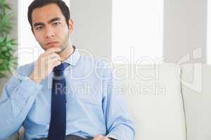 Thoughtful classy businessman sitting on cosy sofa